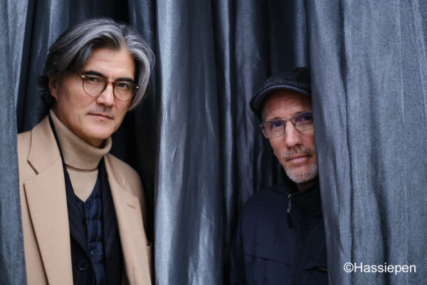 Zwei Männer vor grauem Vorhang
