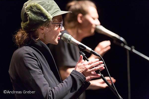 zwei Musiker:innen mit Mikrofonen